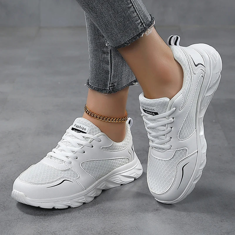 White sneakers worn with gray jeans on a gray floor.