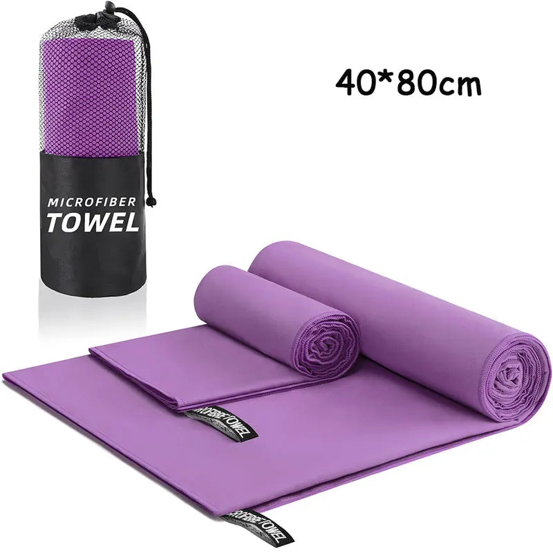 Purple microfiber towel set with carrying bag on a white background