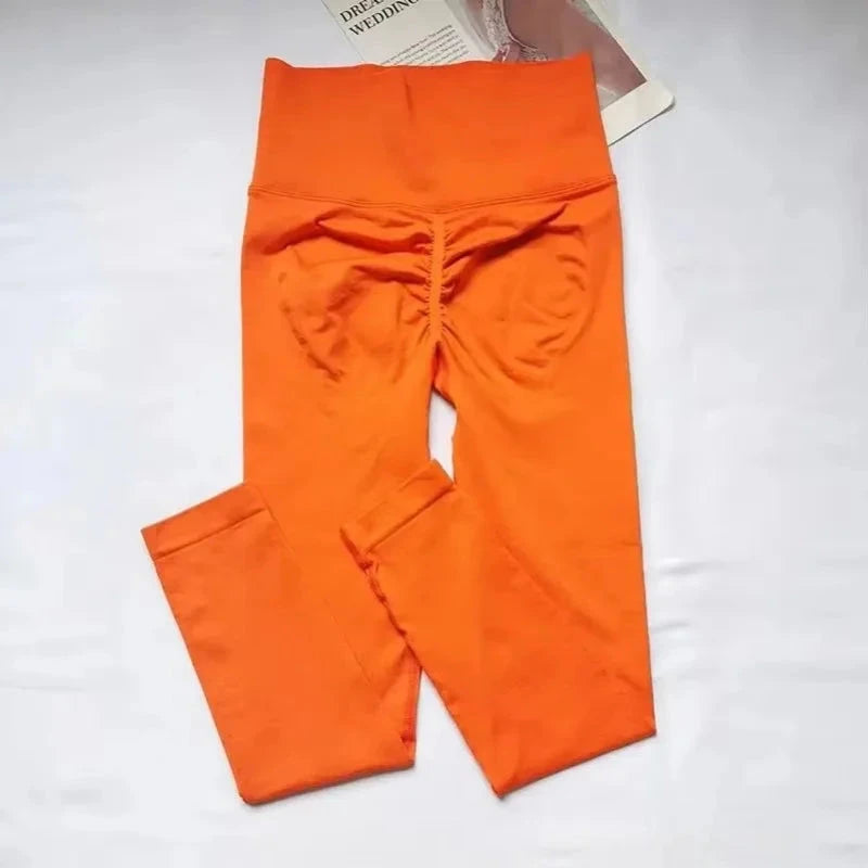 Folded orange seamless leggings with ruched back design, highlighting high waist and push-up support for women’s fitness and yoga wear.