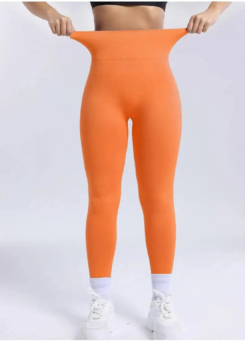 High waist orange seamless leggings for women fitness, demonstrating stretchable waistband and snug fit ideal for gym and running.